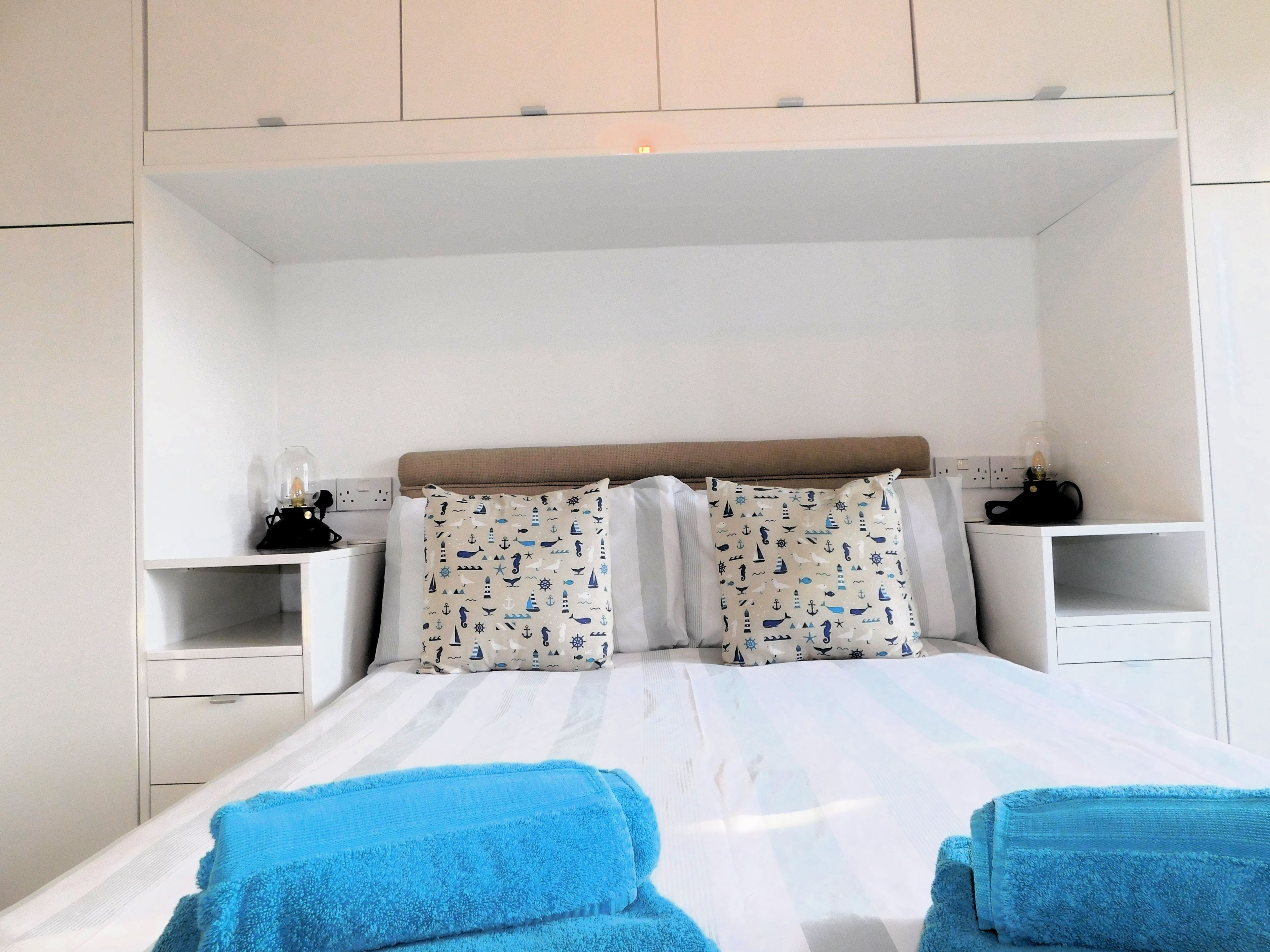A bed with two pillows, a bedside table, and a lamp.