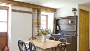 Ein Essbereich mit Holztisch und Stühlen, einer Vase mit Blumen und einem Regal mit Dekoration.