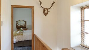 Ein Schlafzimmer mit einem hölzernen Bett, einem Nachttisch, einem Spiegel und einem an der Wand befestigten Hirschkopf.