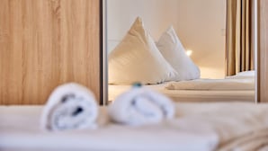 Camera d'albergo con un armadio in legno, un letto con lenzuola bianche e uno specchio che riflette l'ambiente.