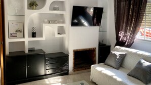 Uma sala de estar moderna com lareira, televisão de tela plana na parede e um espaço de estar aconchegante com almofadas.