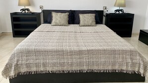 Quarto com uma cama grande, duas mesas de cabeceira e duas luminárias.
