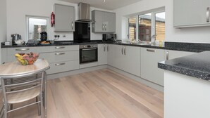 Una cocina moderna con electrodomésticos de acero inoxidable, encimera negra y mesa de comedor de madera.