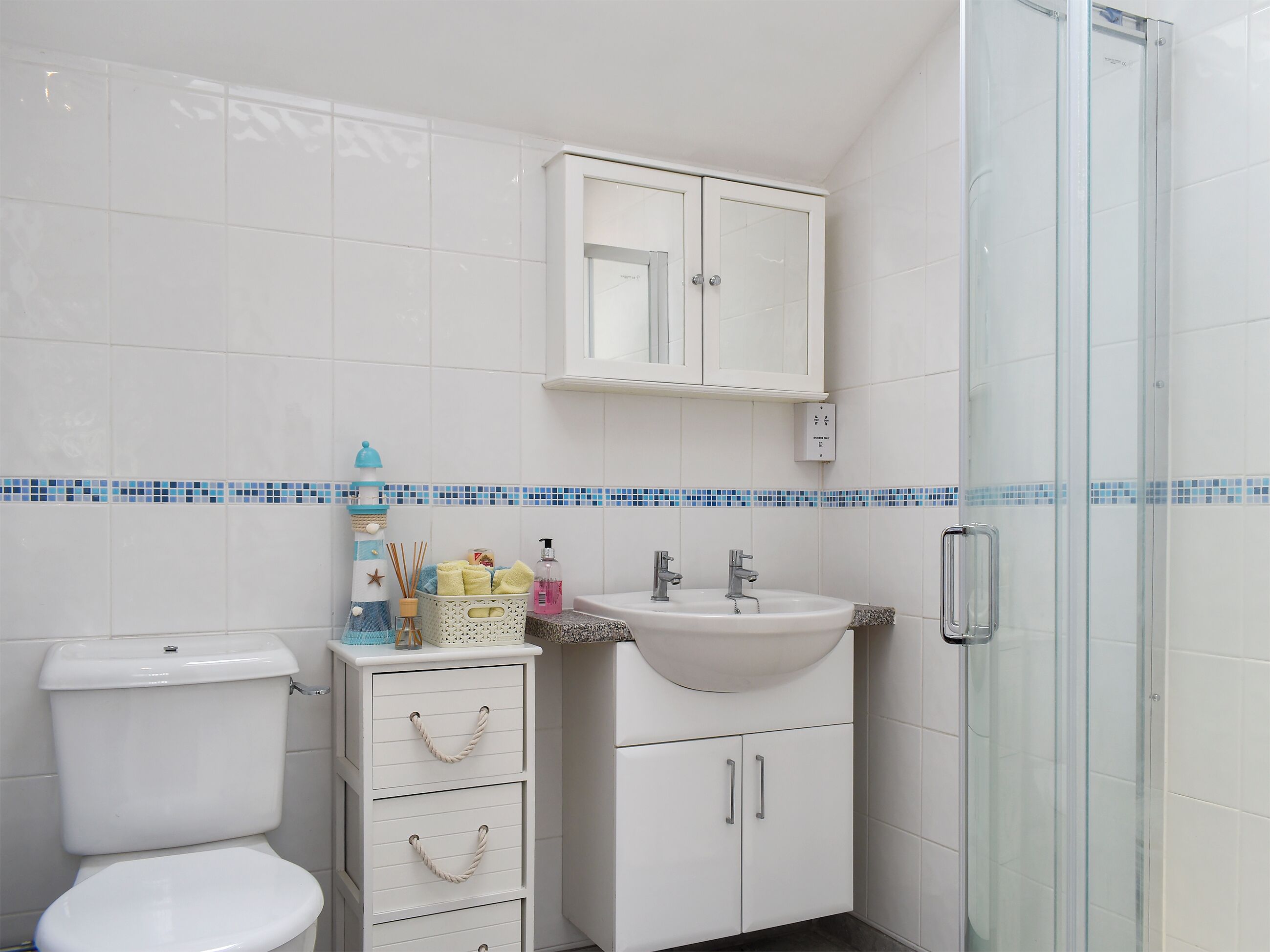 Een badkamer met toilet, wastafel, kast en een douchecabine van glas.