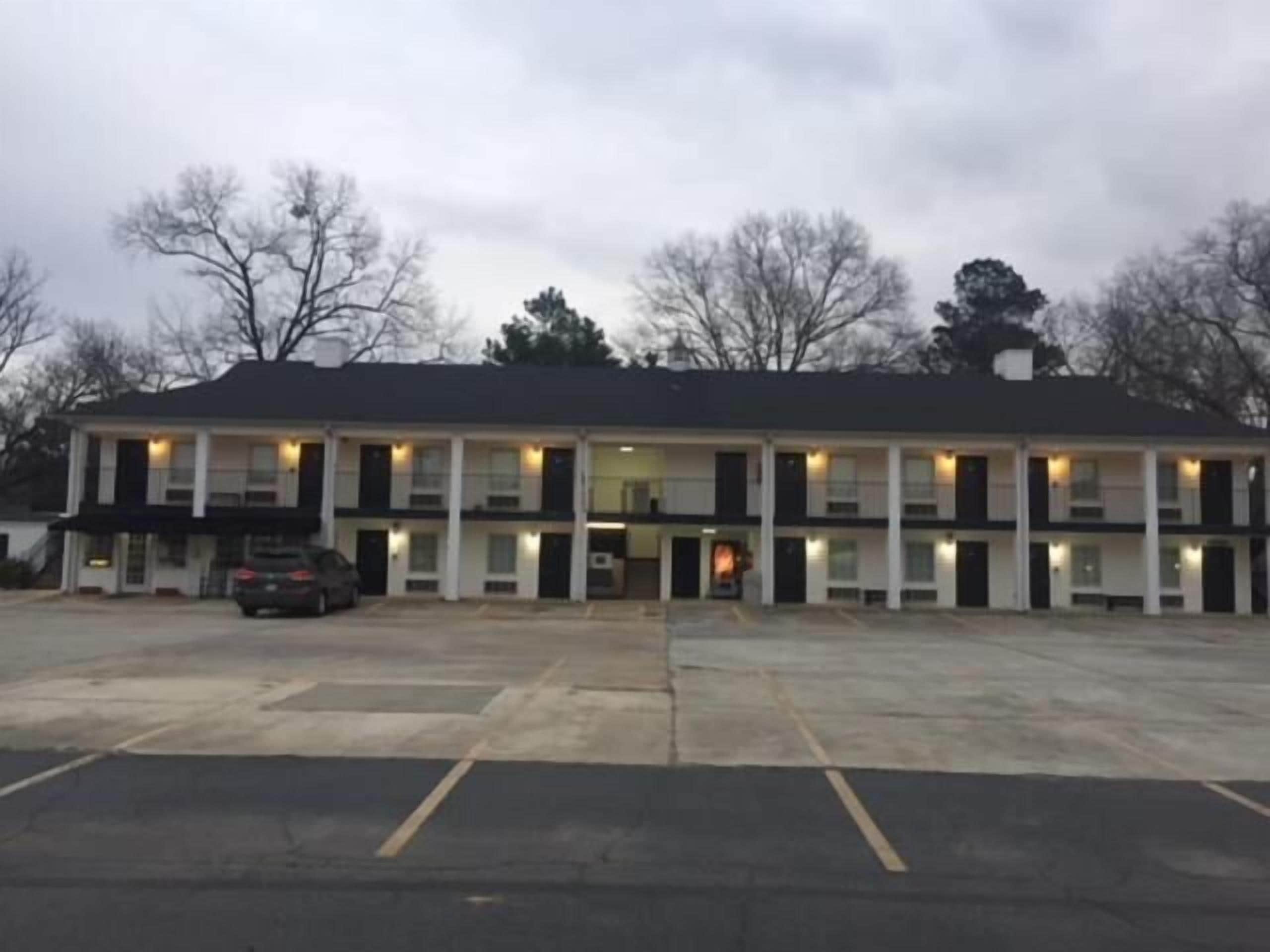 A two-story motel with a central entrance and a parking lot in front.