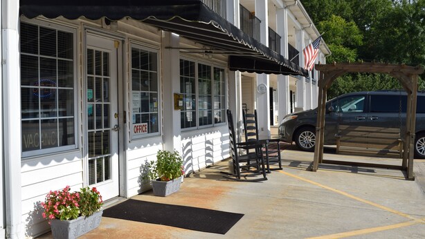A building with a black awning, a parked SUV, and a wooden pergola. - Cullars Inn (Lincolnton)