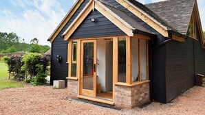 A modern house with a dark exterior, a wooden gable roof, and a glass door entrance. - 2 bedroom accommodation in Canon Frome, near Ledbury (Canon Frome, near Ledbury)