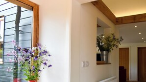 A hallway with a wooden floor, white walls, a window with a view of a building, and a radiator. - 2 bedroom accommodation in Canon Frome, near Ledbury (Canon Frome, near Ledbury)