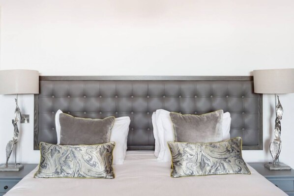 A bedroom with a tufted headboard, two nightstands, and decorative lamps. - Unique Flat in the Heart of New Town (Edinburgh)