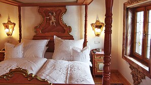 Una cama con dosel con sábanas blancas, dos apliques de pared y una ventana con vistas.