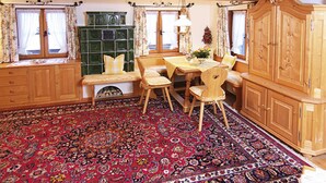 Una habitación tradicional con un banco de madera, una mesa de comedor y una alfombra grande con motivos.
