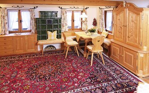 Une pièce au décor traditionnel, avec un banc en bois, une table à manger et un grand tapis à motifs.