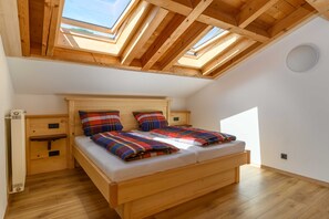 Ein Zimmer mit hohen Decken, einem Oberlicht, einem hölzernen Bett und einem kleinen Nachttisch.