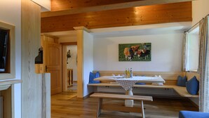 Un interior de madera con una mesa de comedor, bancos y un cuadro de caballos.