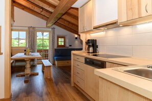 A kitchen with wooden cabinets, a dishwasher, a coffee maker, and a window with a view of greenery.