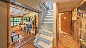 Una escalera con peldaños numerados que conduce a un segundo piso, una chimenea y un interior de madera.