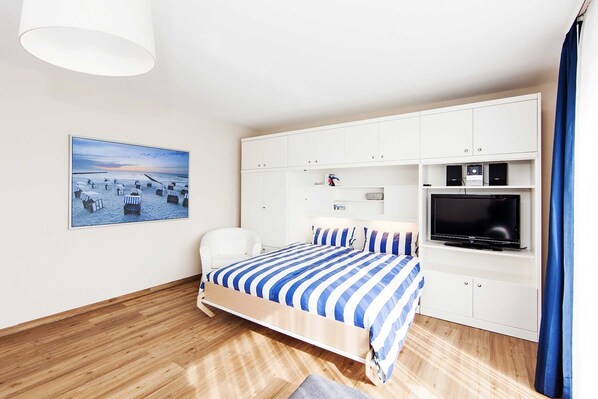 Un dormitorio con una cama, un televisor y un cuadro en la pared.