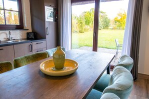A kitchen with a sink, a microwave, and a dining area with a table and chairs. - Country House Type C - Van der Valk Resort Linstow (Dobbin-Linstow)