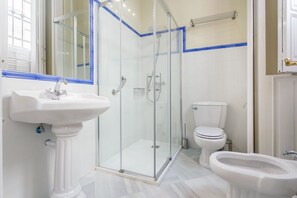 Et moderne badeværelse med en glasafskærmet brusekabine, et pedalvask, toilet og bidet.