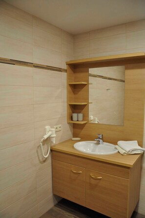 Une salle de bain équipée d’un lavabo, d’un miroir, d’un meuble-lavabo en bois et d’un porte-serviettes.