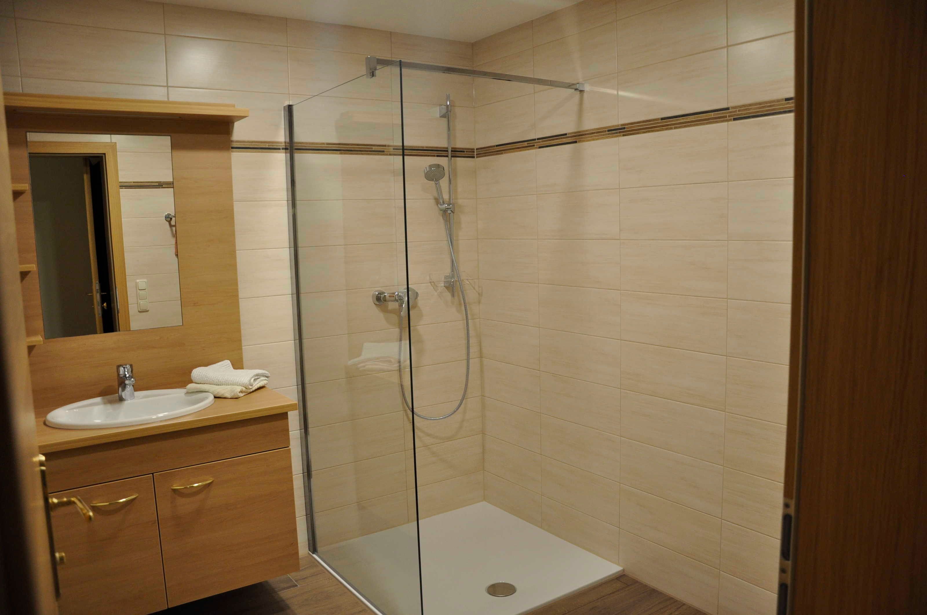 Ein Badezimmer mit einer Duschkabine, einem Waschbecken und einem Holzwaschtisch.