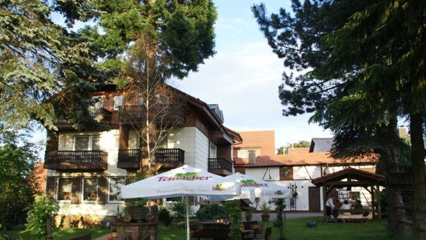 Un edificio con terraza al aire libre y sombrillas, rodeado de árboles.