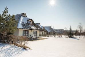 A snow-covered building with a patio area and a clear sky. - Apartment (a) - Van der Valk Resort Linstow (Dobbin-Linstow)