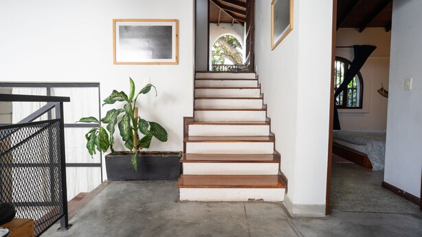 A staircase leading to a second floor with a view of the outdoors. There is a potted plant on the landing and a framed picture on the wall. - Colonial Oasis in Laureles I Patios&Jacuzzi (Medellin)