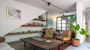A modern living room with a wooden coffee table, wicker furniture, a bookshelf, and a large potted plant. - Colonial Oasis in Laureles I Patios&Jacuzzi (Medellin)