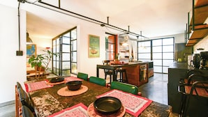 A spacious dining area with a rustic wooden table, green chairs, and a kitchen in the background. - Colonial Oasis in Laureles I Patios&Jacuzzi (Medellin)