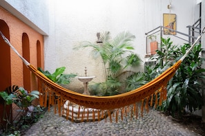 Relax in a serene outdoor space surrounded by lush tropical plants and a tranquil fountain.