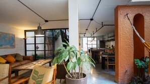 A spacious living area with a large potted plant, a wooden dining table, and a sofa with cushions. - Colonial Oasis in Laureles I Patios&Jacuzzi (Medellin)