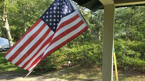 A flagpole with an American flag in a wooded area. - Historic Oak Bluffs home, short walk to town, beach, and harbor. (Oak Bluffs)
