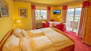 Una habitación de hotel con una cama grande, una mesita, una silla y un televisor.