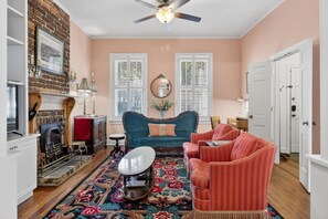 A cozy living room with a fireplace, a blue sofa, a red armchair, and a patterned rug.