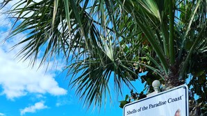 Un panneau d’information placé au bord de la plage, présentant des renseignements sur les coquillages locaux, ainsi qu’une affiche encourageant à préserver la propreté de la plage.