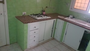 Une cuisine avec des murs verts, des armoires blanches, une cuisinière à gaz et un évier.
