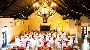 A banquet hall with tables set for a formal event, featuring a chandelier and string lights. - Cowboy corral 2 (Brenham)