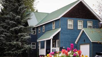 A two-story house with a green roof, a front porch, and a garage.