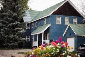 A two-story house with a green roof, a front porch, and a garage. - Townhome in Crested Butte | 3 Bedroom | Walk to Elk | Pet Friendly | Gas Grill (Crested Butte)