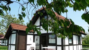 Ett traditionellt hus med korsvirkesfasad och tegeltak, en liten innergård med ett bord och några stolar samt en trädgårdsdel.