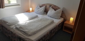 A bed with a patterned headboard, two bedside tables with lamps, and a window with curtains.