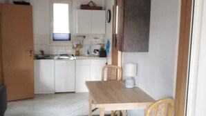 A compact kitchen with white cabinets, a wooden table, and a chair. - House 2 - Holiday home family Acker (Lychen)