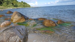 Een strand met grote rotsen in het water en een bebost gebied op de achtergrond.