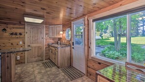 Cocina de estilo cabaña de madera con una ventana grande, armarios de madera y un lavabo empotrado.