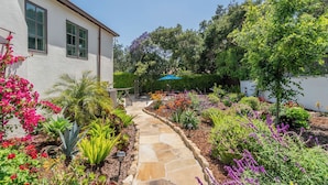 Un giardino curato con un vialetto in pietra che conduce a una casa con ampie finestre.