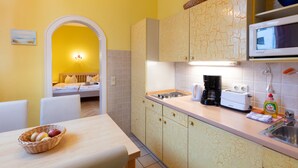 A kitchen with a microwave, toaster, and coffee maker. There is a basket of fruit on the table and a sink with a dish soap bottle. - Apartment 01 - House By the sea (Heringsdorf)