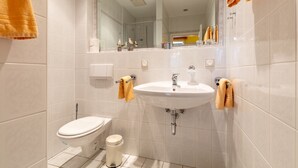 A bathroom with a toilet, sink, and mirror. - Apartment 01 - House By the sea (Heringsdorf)