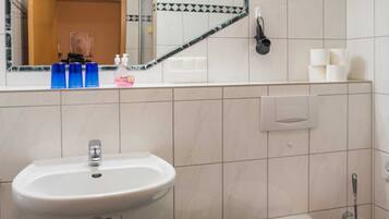 A bathroom with a sink, toilet, and a mirror reflecting a door and toiletries.