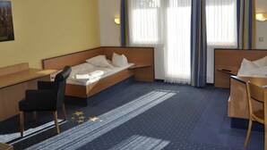 A hotel room with a bed, a desk, a chair, and a window with curtains. - Double room TWIN (3) - sleep & go Hotel Magdeburg GmbH (Magdeburg)